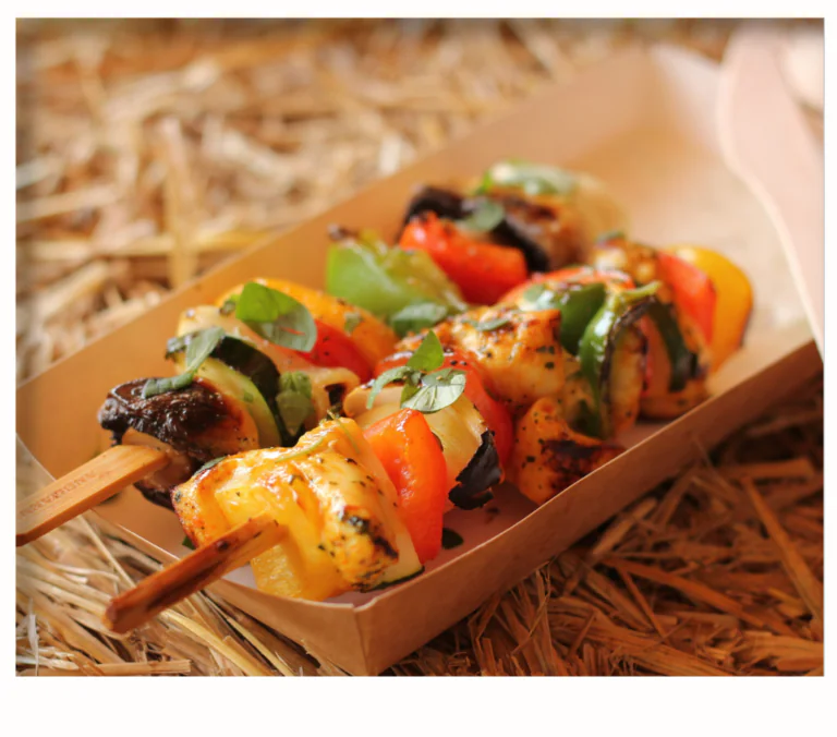 Grilled skewers with colorful peppers, mushrooms and cubed protein, garnished with herbs in tray